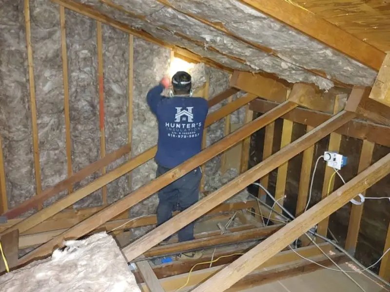 Crew member installing attic wall insulation